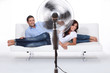 Man and woman laid on a sofa being ventilated by fan