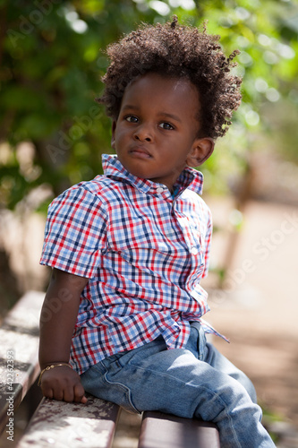 Photo: Outdoor portrait of a black baby sited on a bench Outdoor portrait of a black baby sited on a bench