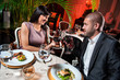 Foto: Beautiful couple with glasses of red wine at restaurant on roman Beautiful couple with glasses of red wine at restaurant on roman