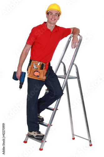 Photo: tradesman standing on a stepladder and holding a screw gun tradesman standing on a stepladder and holding a screw gun