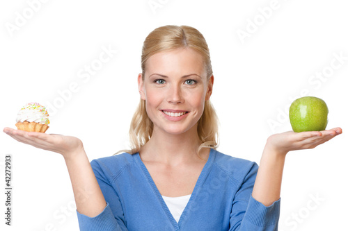 Photo: Attractive woman makes a tough choice between cake and apple Attractive woman makes a tough choice between cake and apple