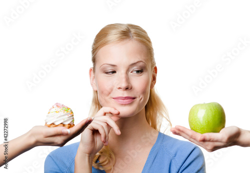 Photo: Beautiful woman makes a tough choice between cake and apple Beautiful woman makes a tough choice between cake and apple