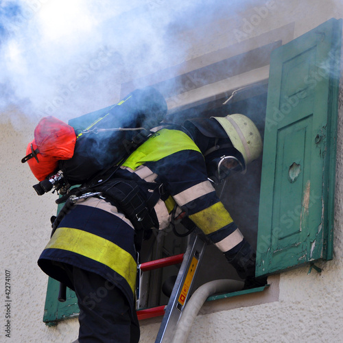 Foto: Feuerwehrmann mit Atemschutz am Fenster Feuerwehrmann mit Atemschutz am Fenster