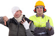 Healthy construction worker standing next to an injured man