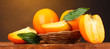 Appetizing persimmons in pad on wooden