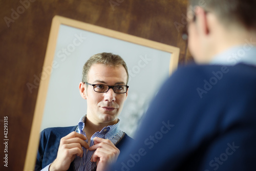 Photo: Young man dressing up and looking at mirror Young man dressing up and looking at mirror