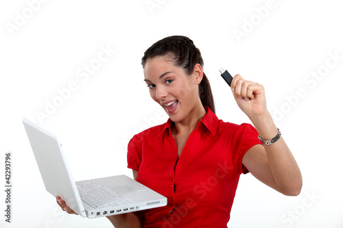 Foto: Woman holding laptop and USB key Woman holding laptop and USB key