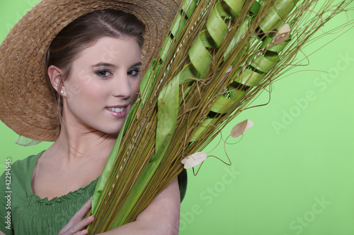 Photo: Woman in hat holding large leaves Woman in hat holding large leaves