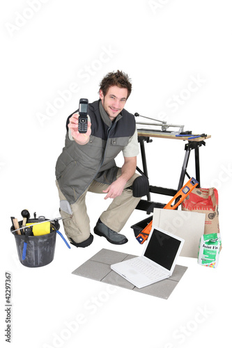 Photo: young craftsman with laptop showing phone young craftsman with laptop showing phone