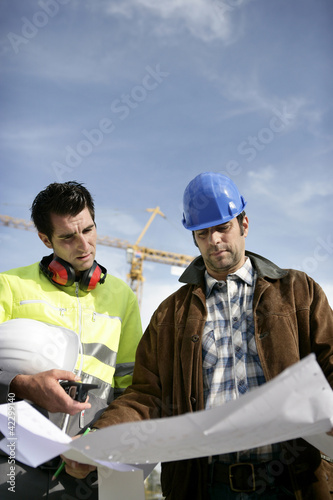 Photo: Tradesman and an engineer examining a blueprint Tradesman and an engineer examining a blueprint