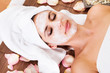 Beautiful young woman getting facial mask