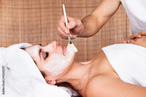 Photo: Beautiful young woman getting facial mask Beautiful young woman getting facial mask
