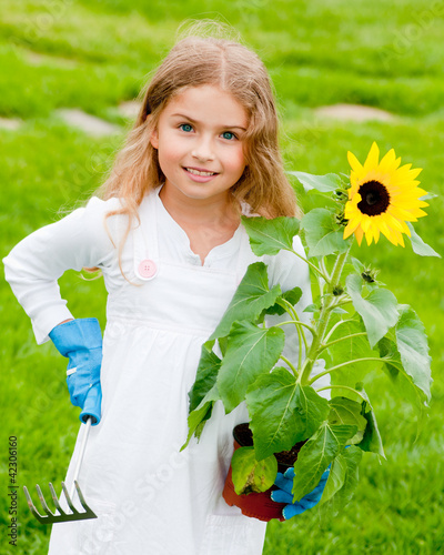 Photo: Gardening - lovely girl planting sunflower Gardening - lovely girl planting sunflower