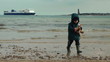 Boy on the beach with huge ferry, slow motion