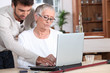 Photo: Young man helping a senior with a laptop computer Young man helping a senior with a laptop computer