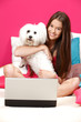 happy teenager sitting in her bed with her white dog