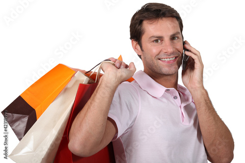 Photo: Man shopping and talking on his mobile phone Man shopping and talking on his mobile phone