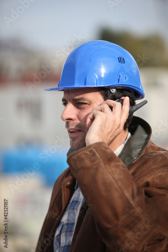 Foto: Construction worker speaking into his walkie-talkie Construction worker speaking into his walkie-talkie