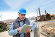 Photo: Construction manager controlling building site with plan Construction manager controlling building site with plan