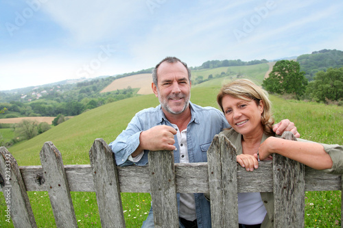 Photo: Senior couple leaning on fence in countryside Senior couple leaning on fence in countryside