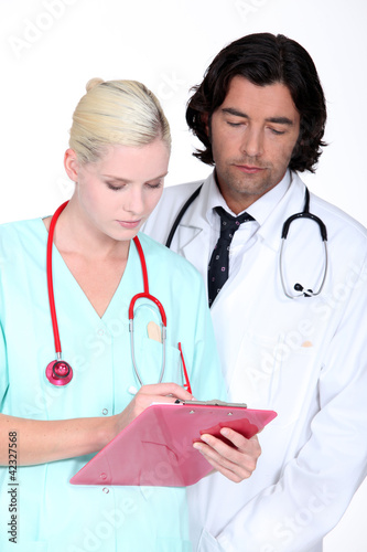 Foto: a doctor and a nurse looking seriously a paper a doctor and a nurse looking seriously a paper