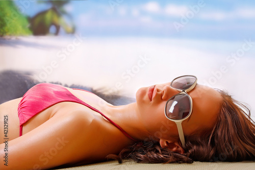 Photo: A beautiful woman taking a sun bath on a beach A beautiful woman taking a sun bath on a beach