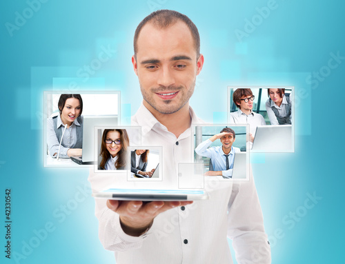 Photo: Adult businessman using his tablet computer to communicate his t Adult businessman using his tablet computer to communicate his t