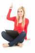 smiling young woman wiith laptop pointing up, full length