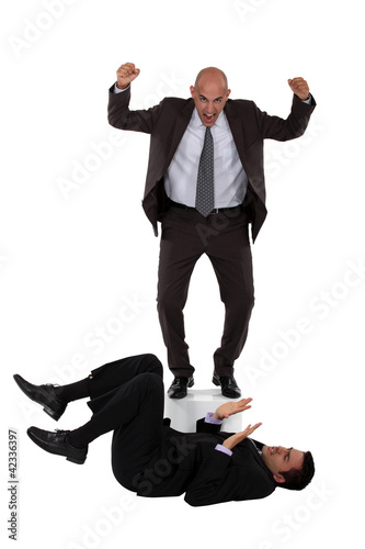 Photo: Angry boss shouting at employee laying on the floor Angry boss shouting at employee laying on the floor