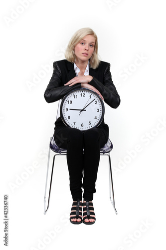 Photo: Woman sitting with a clock on her knees Woman sitting with a clock on her knees