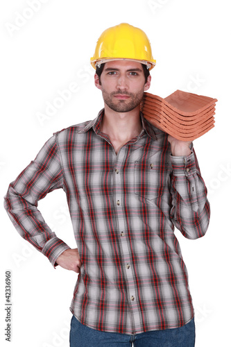Photo: Builder holding stack of roof tiles Builder holding stack of roof tiles