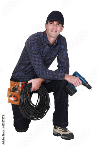 Photo: Handyman with power drill kneeling Handyman with power drill kneeling