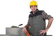 bricklayer posing near wall with arm akimbo