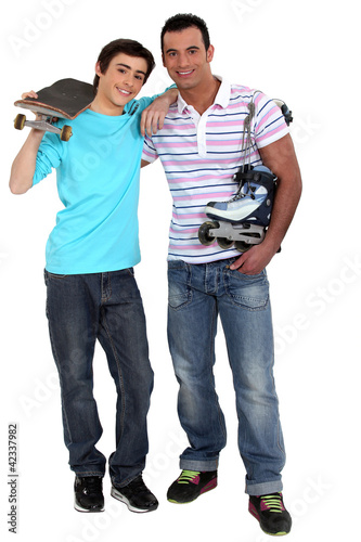 Foto: Man with rollerblades and teen carrying skateboard Man with rollerblades and teen carrying skateboard