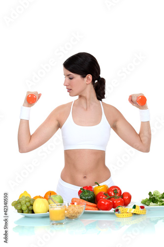 Photo: Woman lifting weights surrounded by vegetables Woman lifting weights surrounded by vegetables