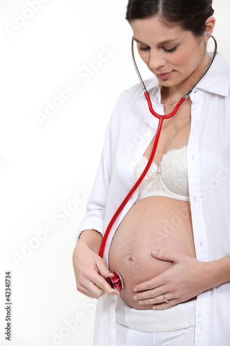 Photo: Pregnant woman listening to her baby's heartbeat Pregnant woman listening to her baby's heartbeat