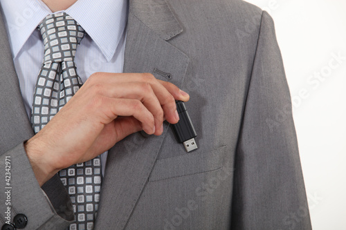 Photo: businessman putting a flash drive in his pocket businessman putting a flash drive in his pocket