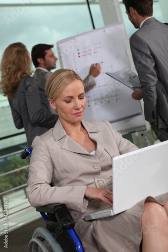 Foto: Female executive in wheelchair using laptop computer Female executive in wheelchair using laptop computer