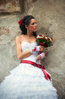 Photo: Beautiful bride with bouquet leaning against the wall (profile) Beautiful bride with bouquet leaning against the wall (profile)