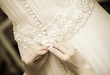 Photo: Detail of bridesmaid fixing bride's wedding dress Detail of bridesmaid fixing bride's wedding dress