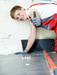 Handsome apprentice lays tiles and showing thumb up in site