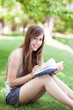 Photo: Young woman reading book outdoors Young woman reading book outdoors