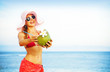 Young woman in pink swimsuit with coconut cocktail on the beach,