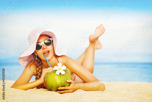 Photo: Young woman in pink swimsuit with coconut cocktail on the beach, Young woman in pink swimsuit with coconut cocktail on the beach,