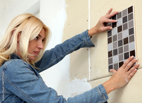 Photo: Young woman choose tiles Young woman choose tiles