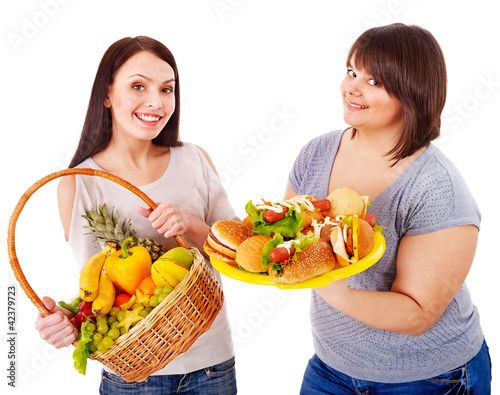 Foto: Women choosing between fruit and hamburger. Women choosing between fruit and hamburger.