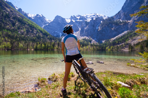 Photo: Yaung woman riding a bike beside Alpine lake Yaung woman riding a bike beside Alpine lake