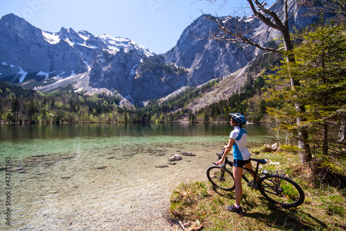 Photo: Yaung woman riding a bike beside Alpine lake Yaung woman riding a bike beside Alpine lake