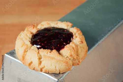 Photo: Single raspberry thumbprint cookie on metal box Single raspberry thumbprint cookie on metal box