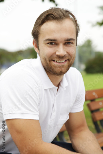 Photo: Sportlicher junger Mann auf Parkbank Sportlicher junger Mann auf Parkbank